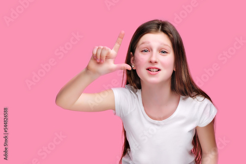 Funny girl showing looser gesture against pink background photo