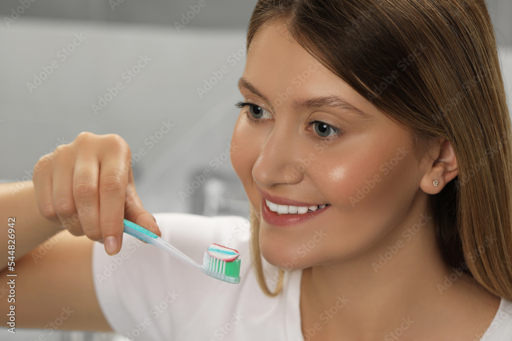 Young woman holding brush with toothpaste in bathroom Young woman holding brush with toothpaste in bathroom