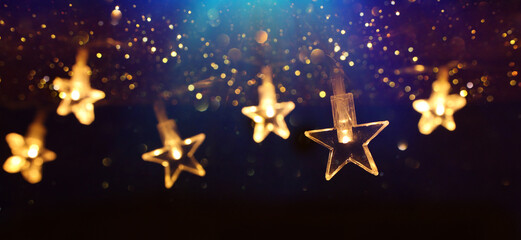 Christmas warm gold garland lights over dark background with glitter overlay