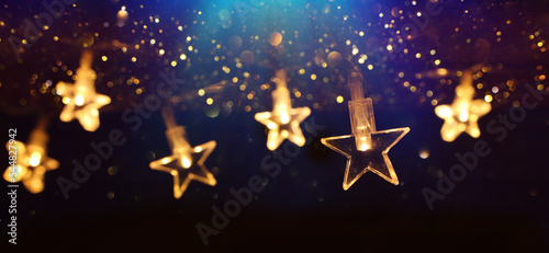 Photographie Christmas warm gold garland lights over dark background with glitter overlay