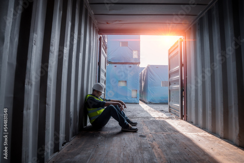 Engineer or worker sit close to cargo container look like tired after work in workplace area for long time and look serious with work is worker business industry concept.