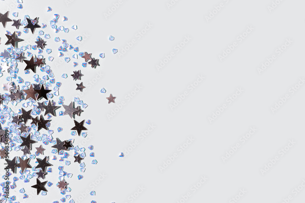 Shiny silver stars and crystals confetti on a blue background. Glowing concept with copy space. Shiny silver stars and crystals confetti on a blue background. Glowing concept with copy space.