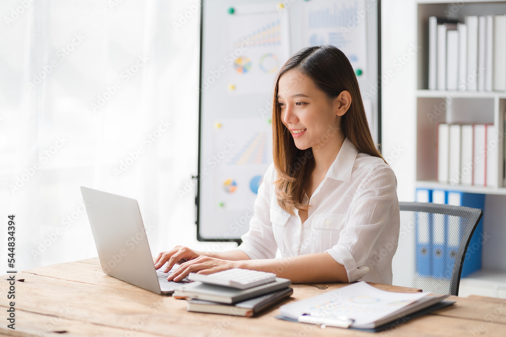 Charming asian businesswoman sitting working on laptop in office. Charming asian businesswoman sitting working on laptop in office.