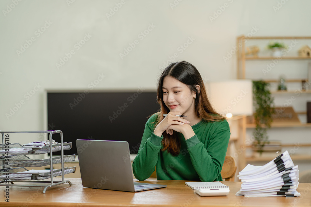 young asian woman working with piles of financial graph chart documents Planning and analyzing marketing data with a laptop on your desk. Company business information office young asian woman working with piles of financial graph chart documents Planning and analyzing marketing data with a laptop on your desk. Company business information office