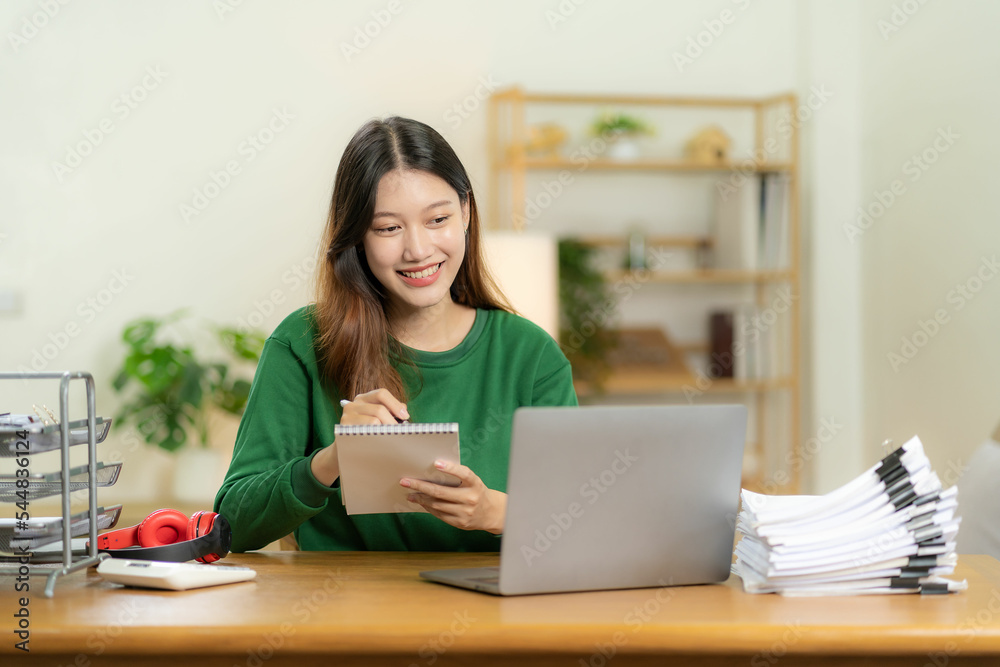 young asian woman working with piles of financial graph chart documents Planning and analyzing marketing data with a laptop on your desk. Company business information office young asian woman working with piles of financial graph chart documents Planning and analyzing marketing data with a laptop on your desk. Company business information office