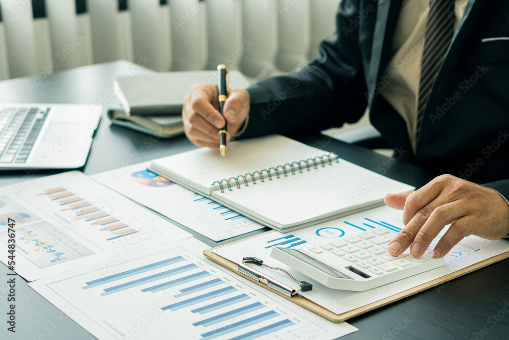 business office concept At her desk, a female accountant presses a calculator for a monthly financial report or company profit. business office concept At her desk, a female accountant presses a calculator for a monthly financial report or company profit.