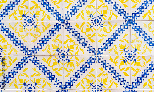 Fragment of building wall with yellow and blue ceramic wall tiles Azulejo Abstract decorative background textured ornate pattern. Traditional ornate Portuguese architecture 