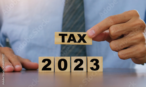 TAX in 2023 concept,Business man holding wooden block. State taxes,tax payment, governant ,finance, tax accounting, statistics and ,tax return, strategy plan, report.new year concept.