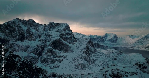 Dramatic Lofoten jagged frozen Svartvatnet head mountain range terrain aerial view orbiting cold sunrise valley photo