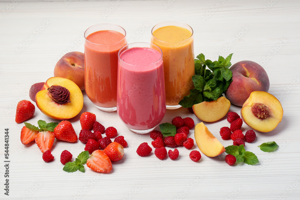 Fresh colorful fruit smoothies and ingredients on white wooden table - obrazy, fototapety, plakaty 