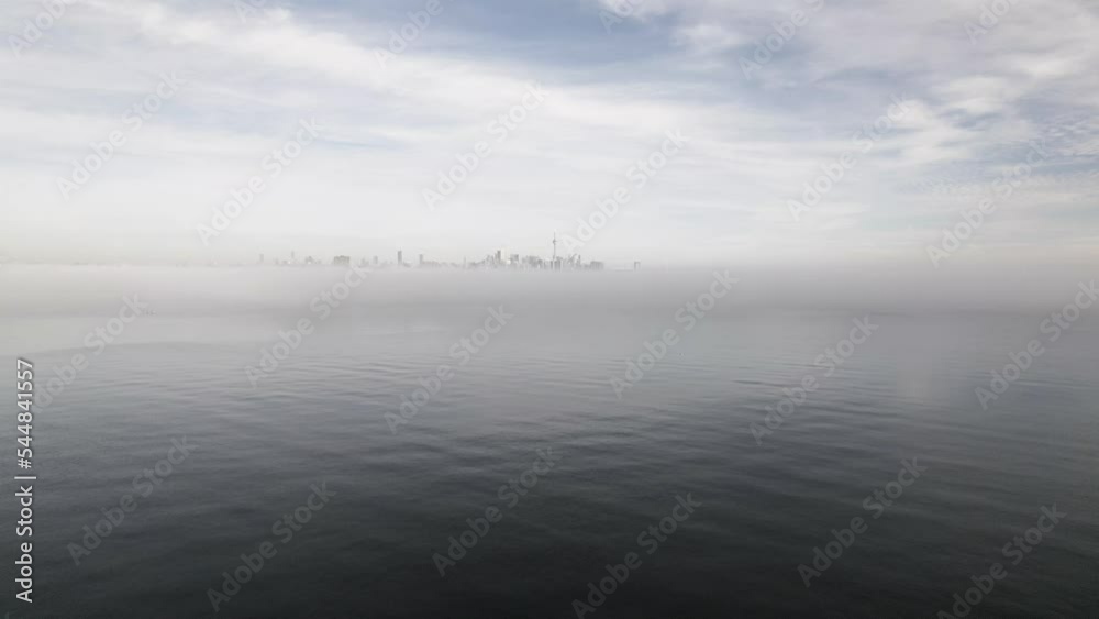 Toronto's Skyline in the distance as viewed from a drone flying over a foggy lake, Toronto, Canada captured by Anthony Saleh Toronto's Skyline in the distance as viewed from a drone flying over a foggy lake, Toronto, Canada captured by Anthony Saleh