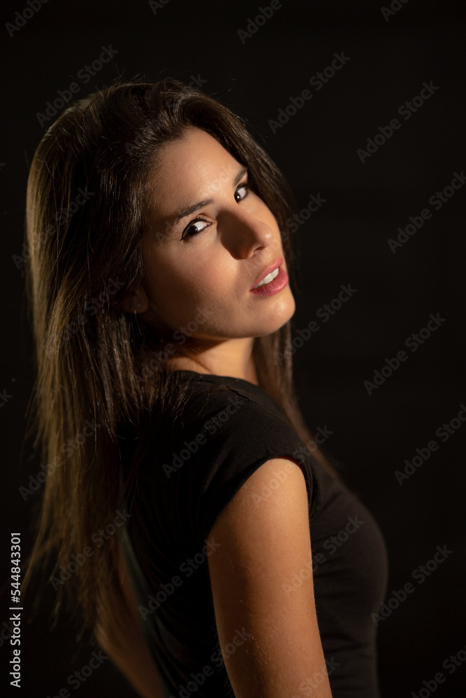 Portrait of a young woman on a black background with a soft, warm and cozy light.