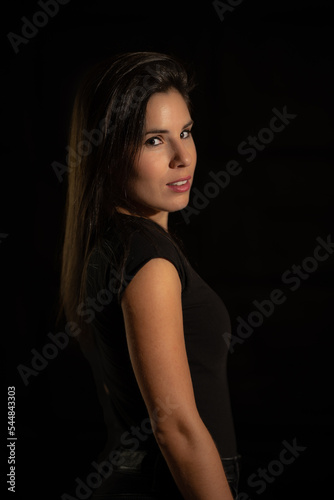 Portrait of a young woman on a black background with a soft, warm and cozy light. © ANGEL LARA FOTO
