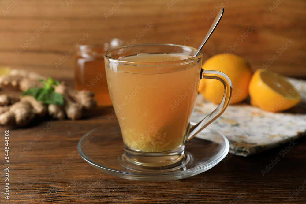Cup of delicious ginger tea and ingredients on wooden table Cup of delicious ginger tea and ingredients on wooden table