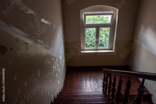The interior of a wooden staircase in an old residential tenement house. Photo taken in natural lighting conditions.