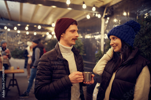 Happy couple in love in romantic dating with hot drinks  enjoying themselves  dressing warmly  looking at each other and smiling.