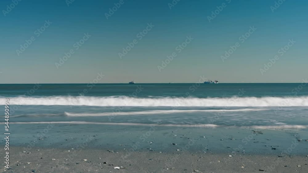 Timelapse of boats on ocean with waves pushing in and out in the foreground. Timelapse of boats on ocean with waves pushing in and out in the foreground.