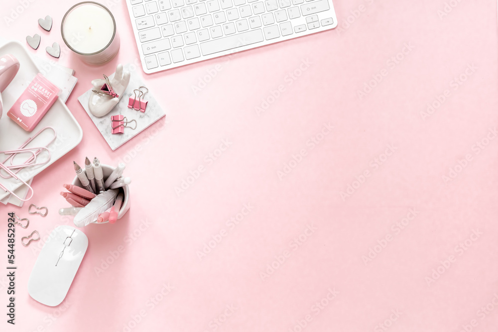 A feminine workspace, keyboard of a computer on pink background with copy space