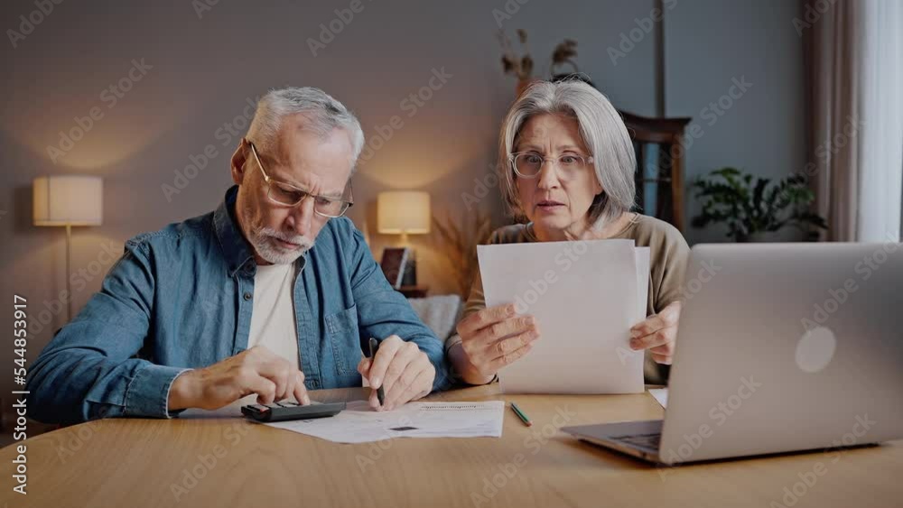Elderly couple counts amount of payments and looks shocked Elderly couple counts amount of payments and looks shocked