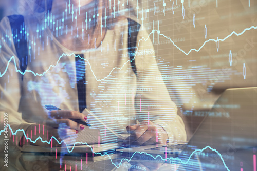 Double exposure of businesswoman hands typing on computer and financial graph hologram drawing. Stock market analysis concept.