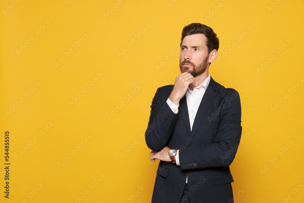 Pensive bearded man in suit looking away on orange background. Space for text Pensive bearded man in suit looking away on orange background. Space for text