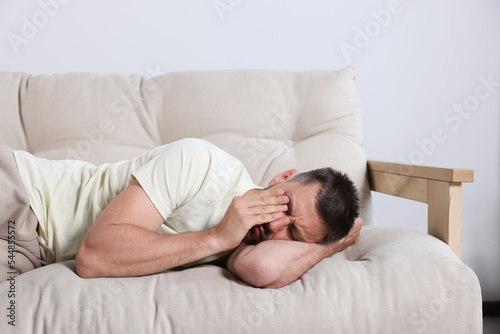 Sleepy man lying on sofa at home