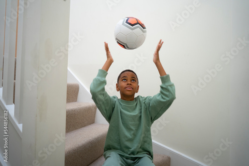 Boy sitting on stairs and throwing soccer ball in air photo