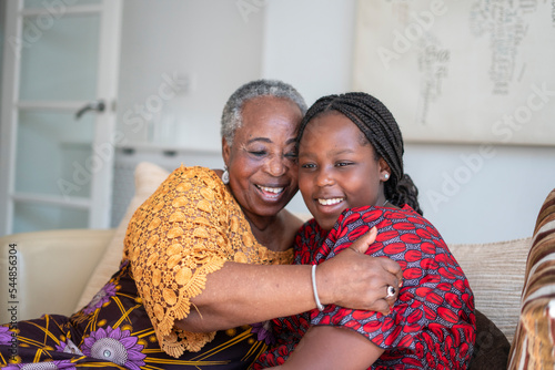 Smiling senior woman hugging teenage granddaughter at home