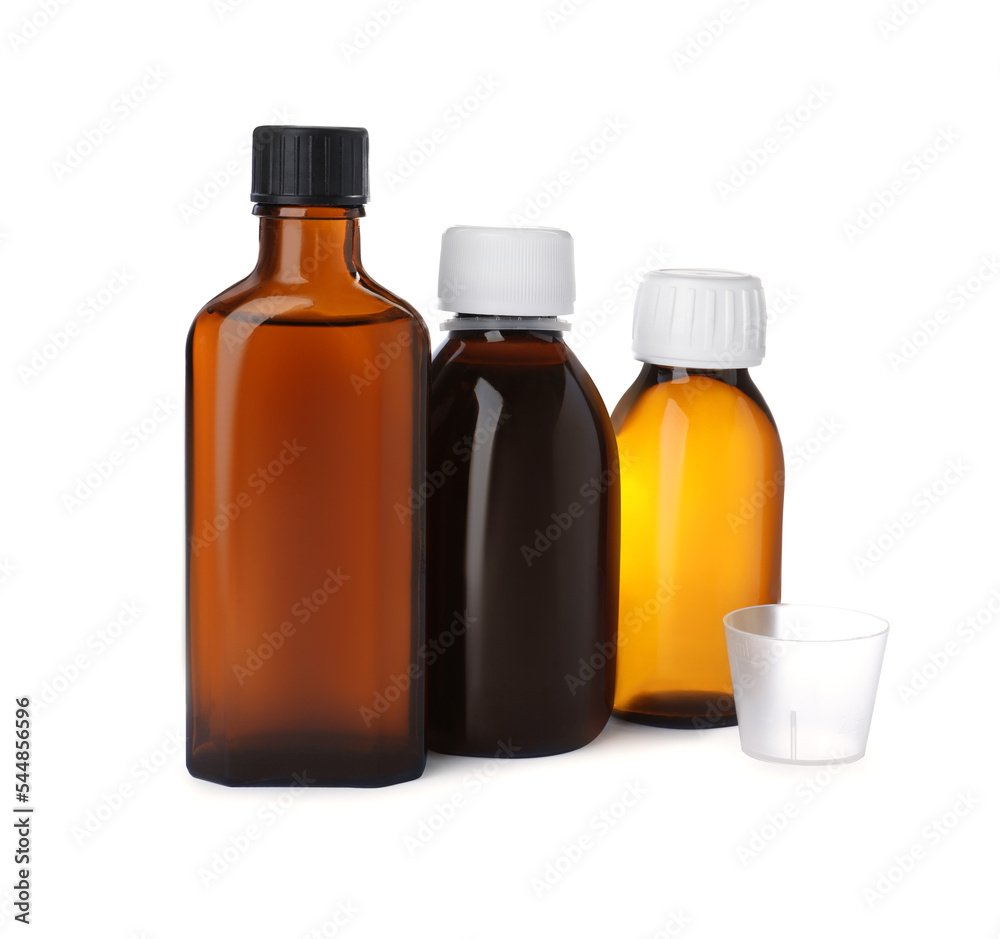 Bottles of syrups with measuring cup on white background. Cough and cold medicine