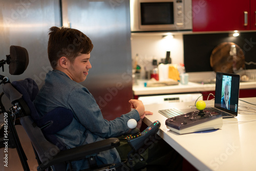 Disabled son talking with father on laptop through video call photo