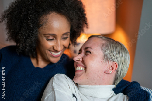 Close-up of smiling lesbian couple embracing at home