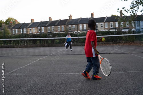 Children playing tennis on neighborhood court photo