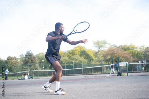 Man playing tennis on neighborhood court photo