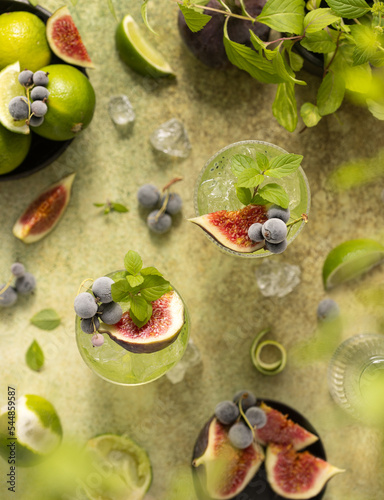 Refreshing cocktails with figs lime currant tonic water gin or vodka on green background and mint leaves.Top view of beautiful drinks.