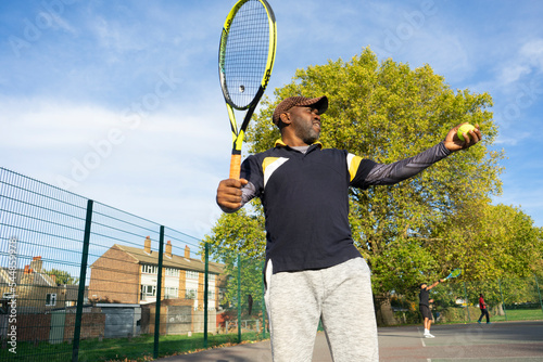 Man playing tennis on neighborhood court © Cultura Creative