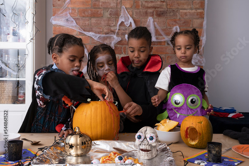 Children in Halloween costumes making Jack OLantern photo