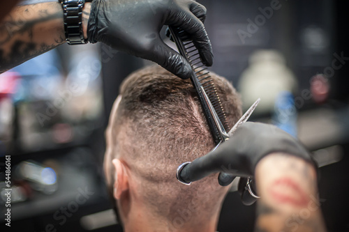Modern urban hairdresser cut hair with hair scissors in professional hairdressing salon and studio. Close-up detail view