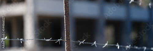 Barbed wire fence in front of prison building closeup photo