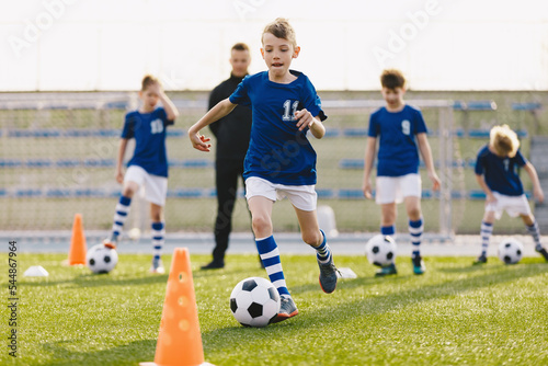 Young European Footballers Dribbling Balls. Happy Kids on Training Soccer Drill. Soccer Boys in Training With School Young Coach © matimix