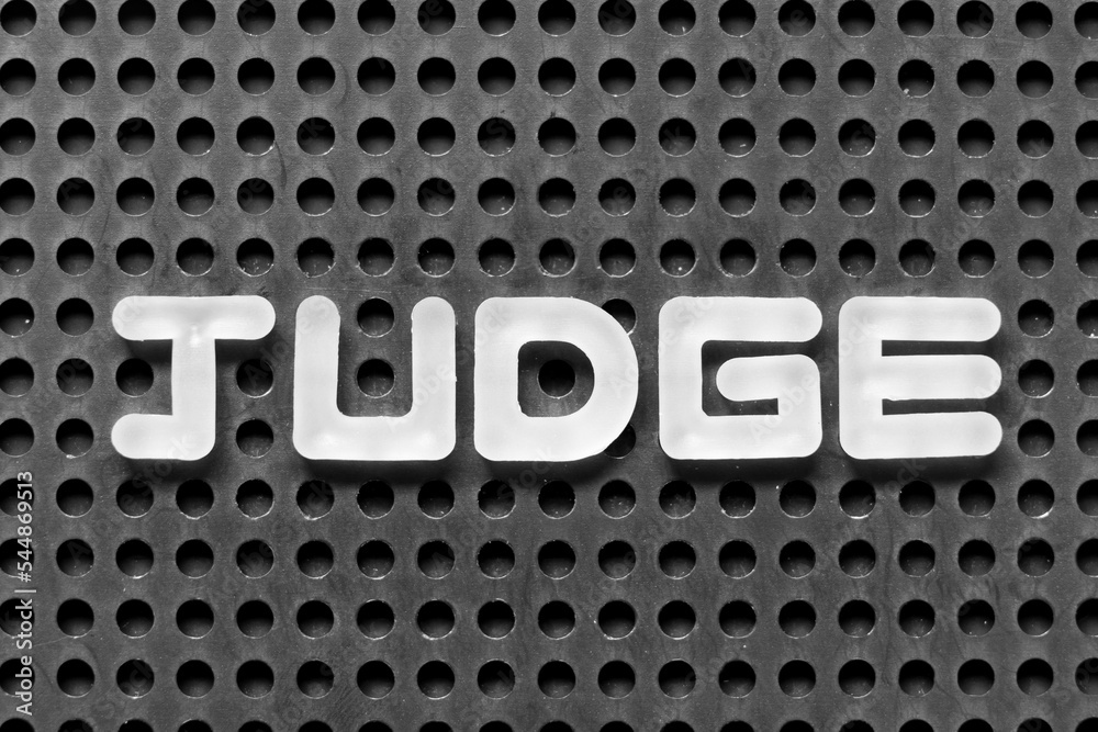 White alphabet letter in word judge on black pegboard background