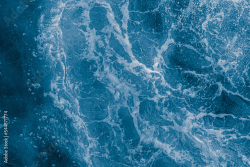 Dark blue sea surface with waves, splash and bubbles