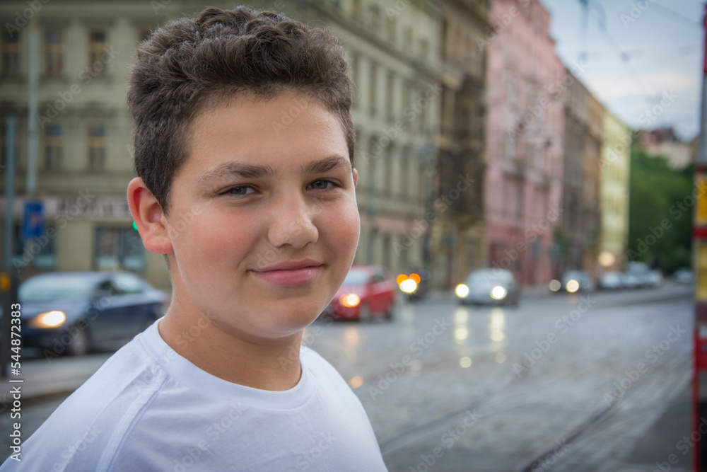 On a summer evening, a boy stands near the road in the city. On a summer evening, a boy stands near the road in the city.