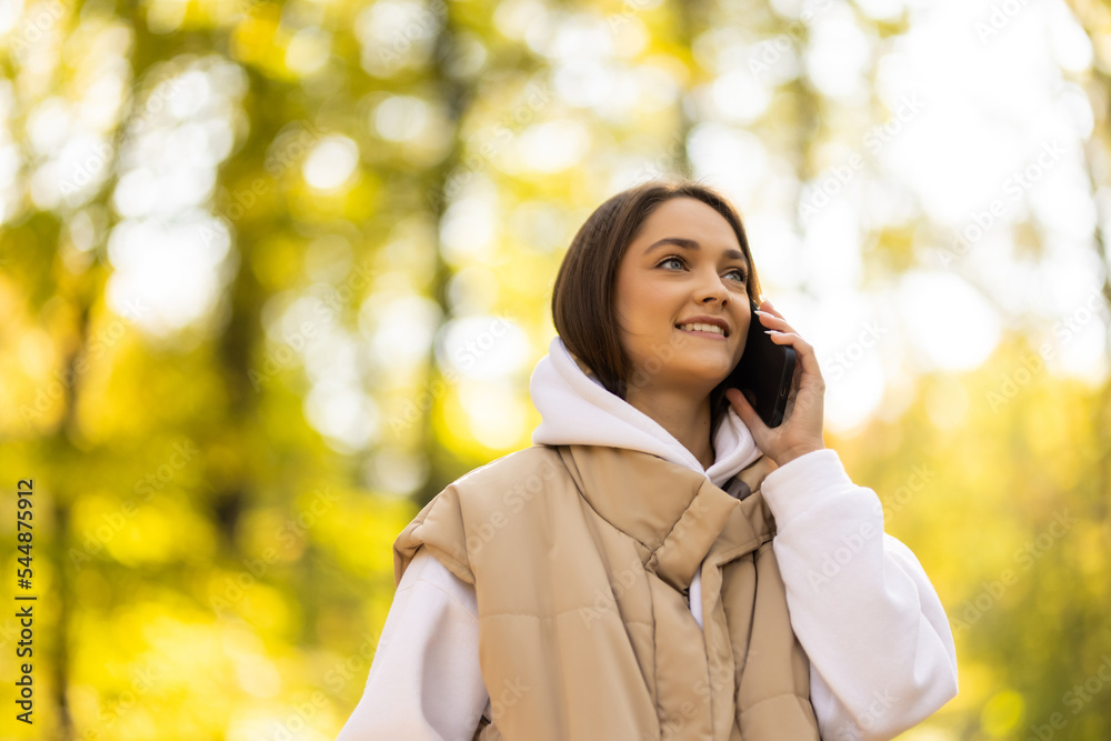 Happy young woman on phone in autumn park Happy young woman on phone in autumn park