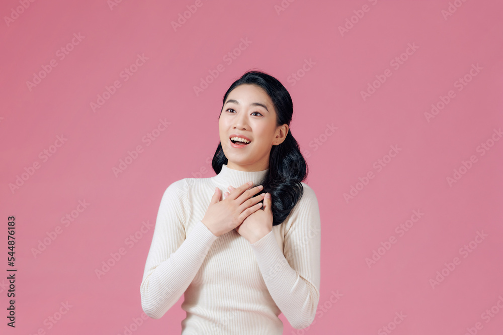 Cheerful woman smiling and holding hands on chest isolated over pink wall Cheerful woman smiling and holding hands on chest isolated over pink wall