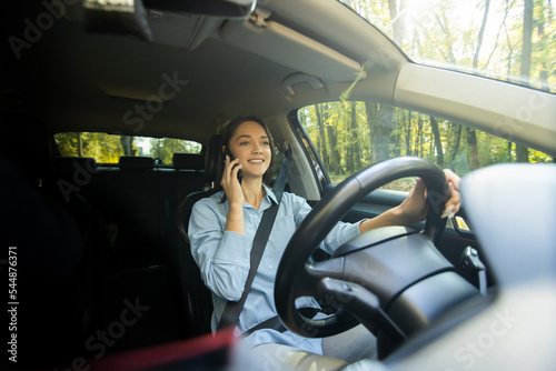 Young businesswoman driving car and talking on cell phone concentrating on the road