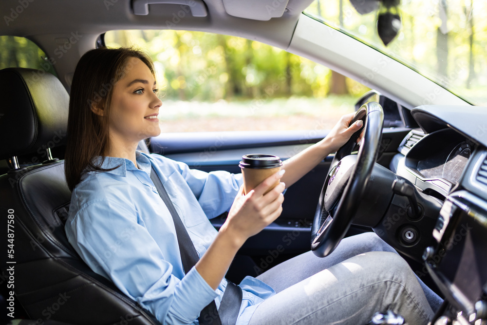 Young woman with coffee to go driving her car