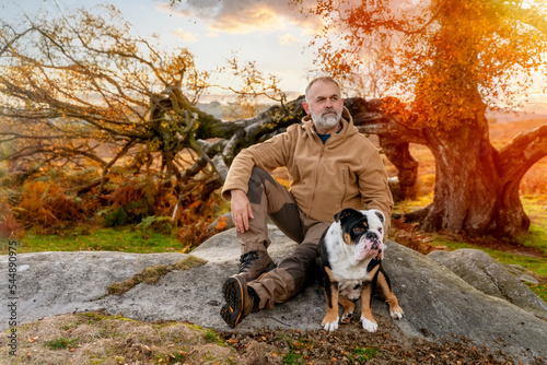 A happy pensioner with English bulldog on a walk is going to play in Autumn park. Dog training. Free time in retirement.