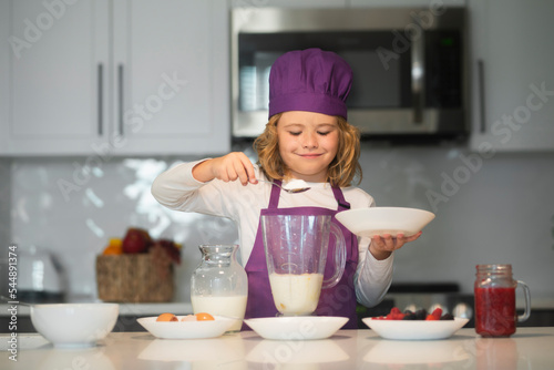 Chef kid preparing tasty food at kitchen. Kids are preparing the dough, bake cookies in the kitchen.