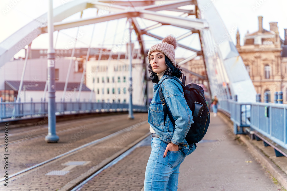 a young woman in a denim jacket is talking on the phone and waiting for a tram at the stop Lifestyle photo a young woman in a denim jacket is talking on the phone and waiting for a tram at the stop Lifestyle photo