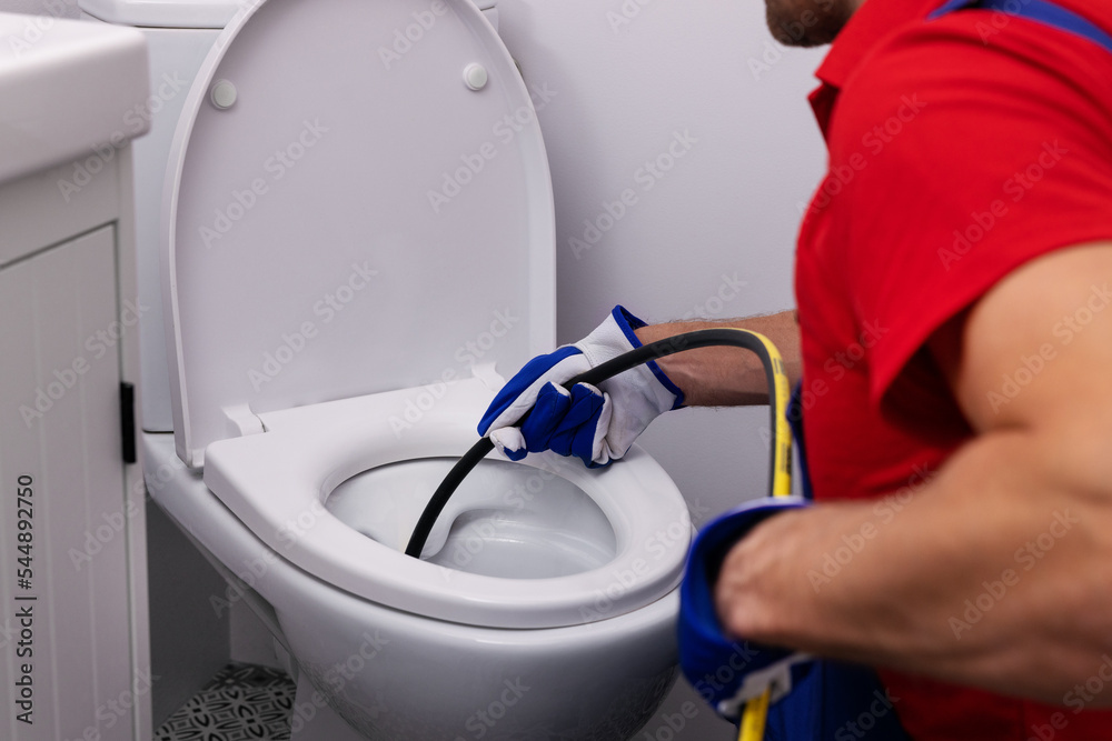 plumber-unclogging-blocked-toilet-with-hydro-jetting-at-home-bathroom